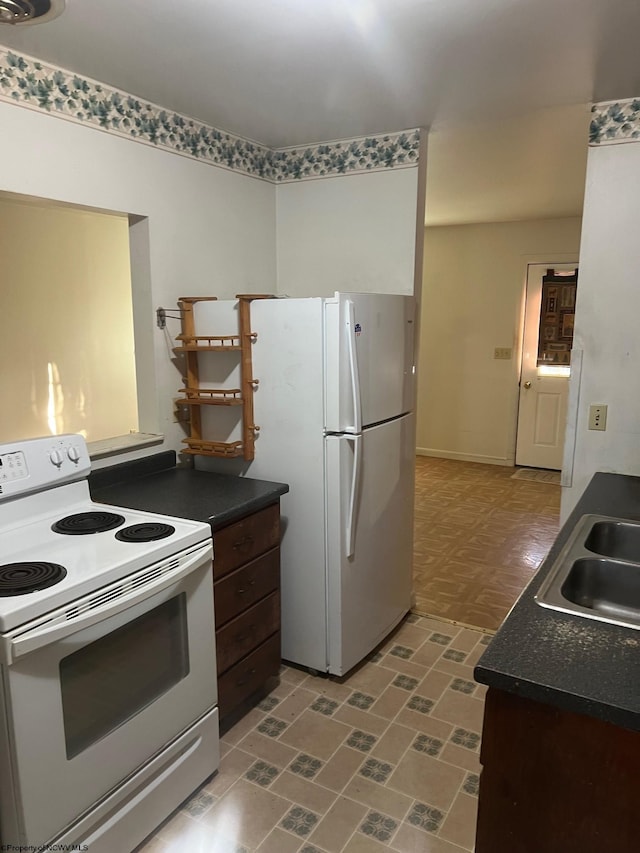 kitchen with dark brown cabinets, white appliances, and sink