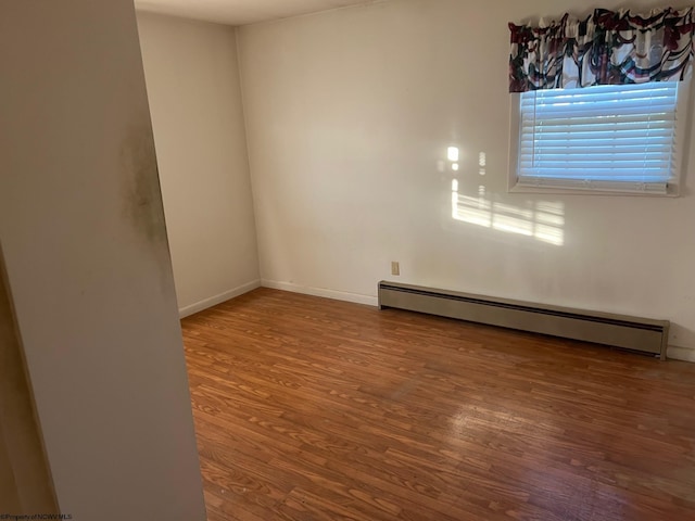 unfurnished room with wood-type flooring and baseboard heating