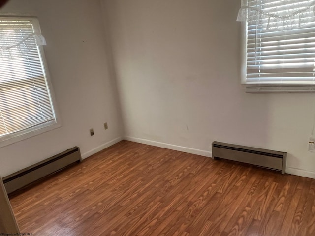 unfurnished room featuring baseboard heating and hardwood / wood-style floors