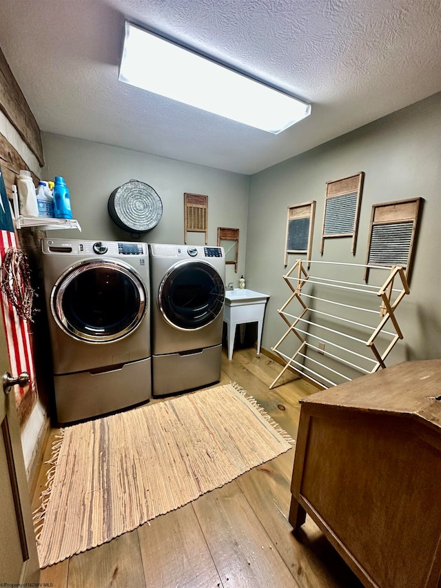 laundry room with a textured ceiling, light wood-type flooring, and independent washer and dryer