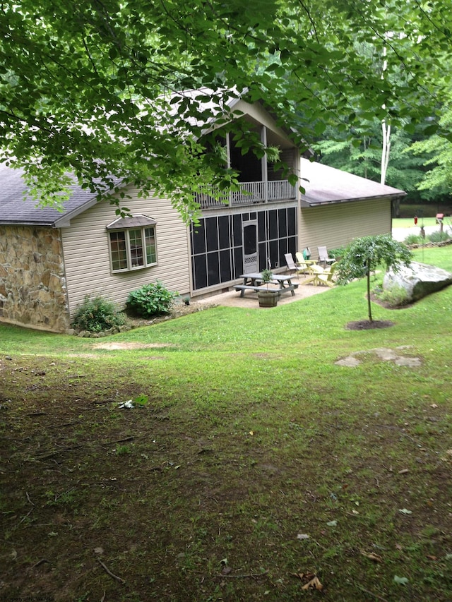 rear view of property featuring a lawn, a patio area, and an outdoor fire pit