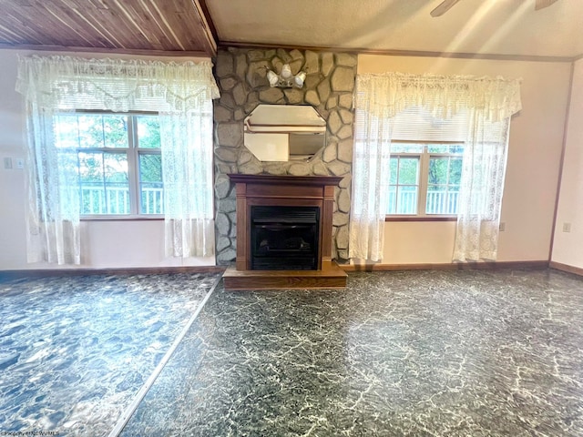 unfurnished living room featuring a fireplace, wood ceiling, a wealth of natural light, and ceiling fan