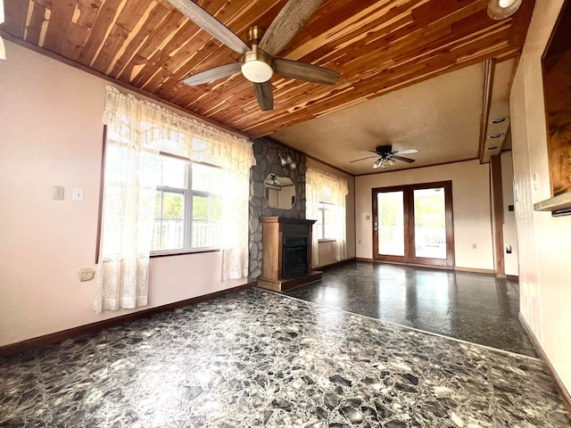 unfurnished living room with ceiling fan, wood ceiling, and plenty of natural light