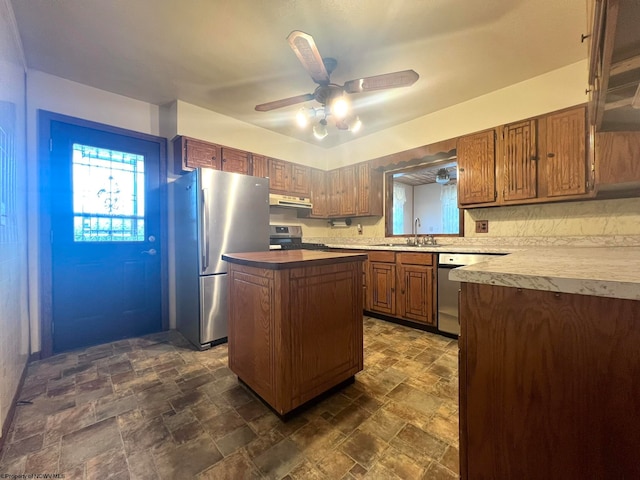 kitchen featuring appliances with stainless steel finishes, a kitchen island, ceiling fan, and sink