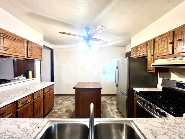 kitchen featuring extractor fan, gas range, sink, a center island, and a textured ceiling