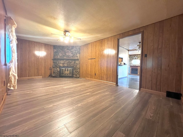 unfurnished living room featuring wood-type flooring, a textured ceiling, a fireplace, and ceiling fan