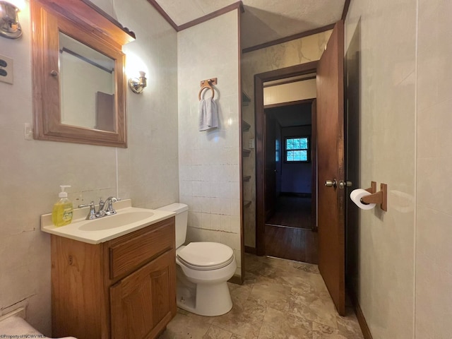 bathroom with vanity, tile walls, and toilet