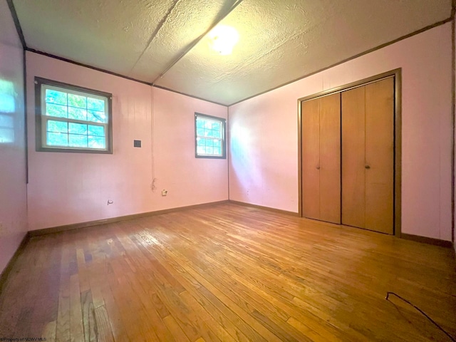 unfurnished bedroom with a closet, light wood-type flooring, and a textured ceiling