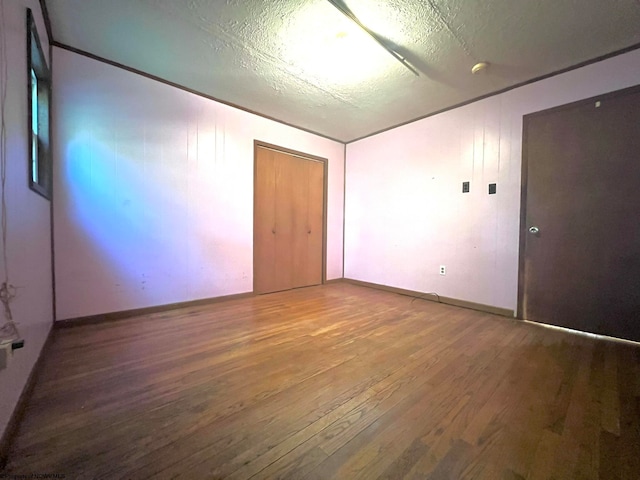 empty room with hardwood / wood-style floors and a textured ceiling