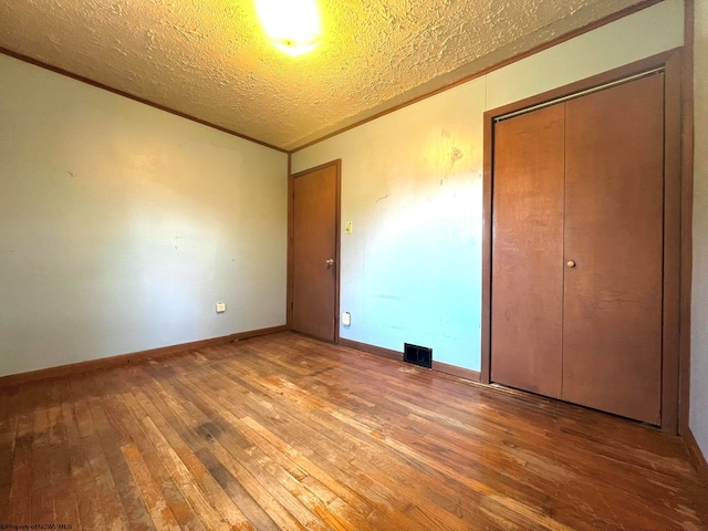 unfurnished bedroom with a textured ceiling, a closet, and hardwood / wood-style flooring