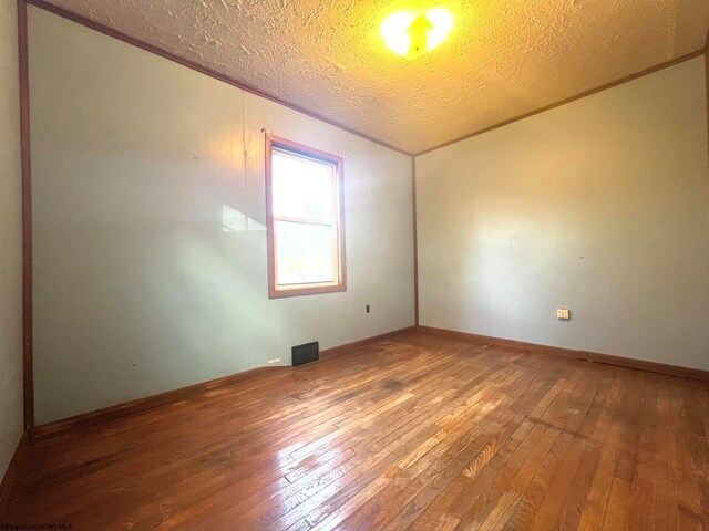 spare room with hardwood / wood-style floors and a textured ceiling