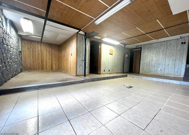 basement featuring wood walls and light tile patterned floors