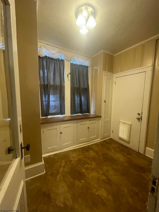 interior space with crown molding, a textured ceiling, and dark colored carpet