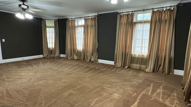 empty room featuring carpet flooring, a healthy amount of sunlight, ornamental molding, and ceiling fan