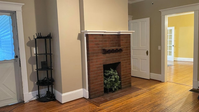 unfurnished living room featuring ornamental molding, a brick fireplace, and hardwood / wood-style flooring