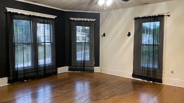 empty room with ornamental molding, a textured ceiling, dark wood-type flooring, and ceiling fan