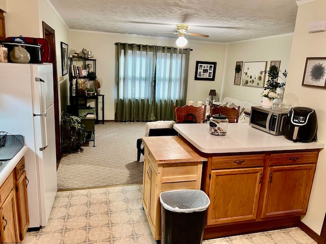 kitchen featuring ceiling fan, white fridge, ornamental molding, light colored carpet, and a textured ceiling