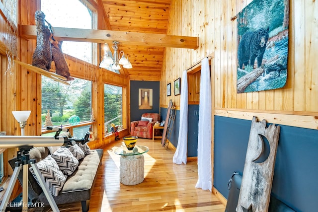 living area with plenty of natural light, hardwood / wood-style floors, a chandelier, and wooden walls