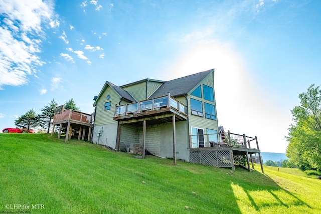 back of house with a deck and a lawn