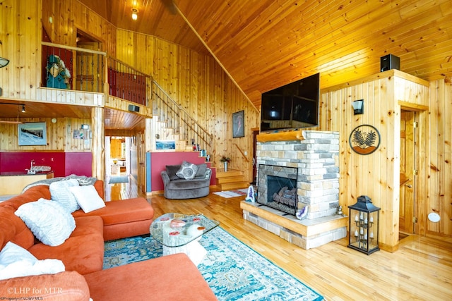 living room with a stone fireplace, wood walls, hardwood / wood-style floors, and wooden ceiling