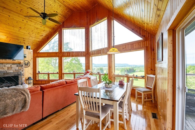 dining space featuring a wealth of natural light, wood walls, and light hardwood / wood-style floors