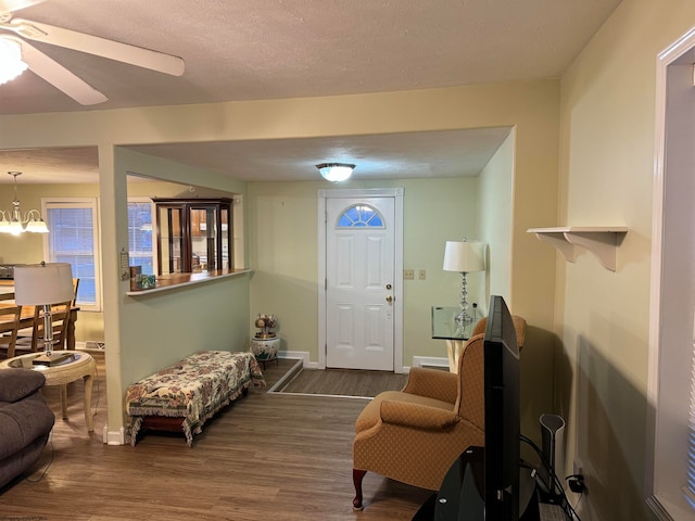 entrance foyer with a textured ceiling, ceiling fan with notable chandelier, and dark wood-type flooring