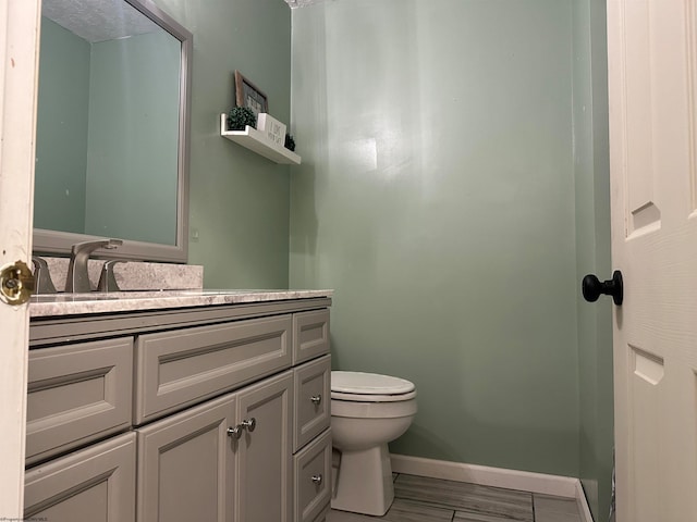 bathroom with vanity, toilet, and hardwood / wood-style floors