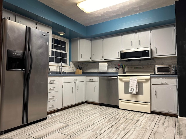 kitchen with backsplash, appliances with stainless steel finishes, and sink