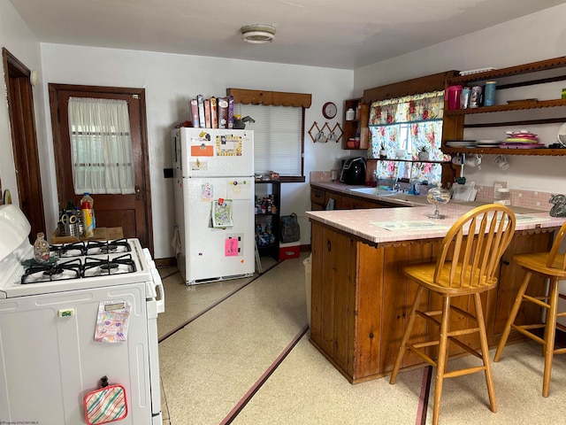 kitchen with white appliances, a breakfast bar, and kitchen peninsula