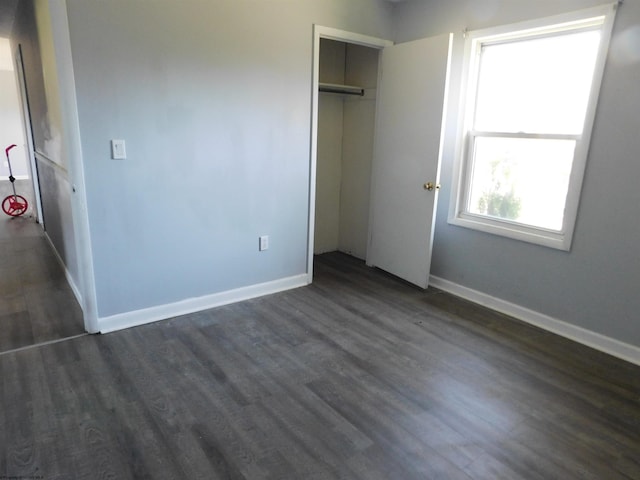 unfurnished bedroom with a closet and dark hardwood / wood-style flooring