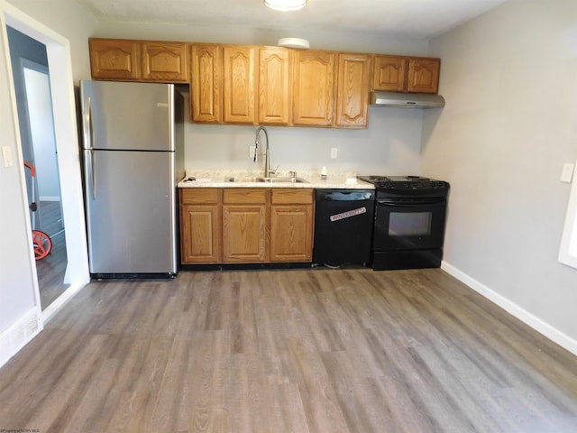 kitchen featuring hardwood / wood-style flooring, black appliances, and sink