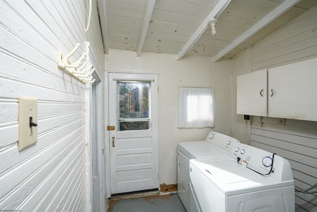 washroom featuring wooden walls, separate washer and dryer, and cabinets