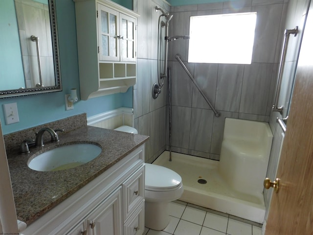 bathroom with vanity, toilet, a wealth of natural light, and tiled shower