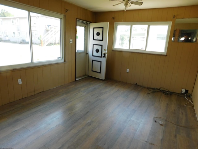 spare room with ceiling fan, a healthy amount of sunlight, wooden walls, and hardwood / wood-style floors