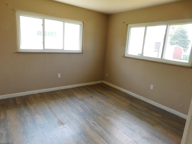 spare room featuring a wealth of natural light and dark wood-type flooring