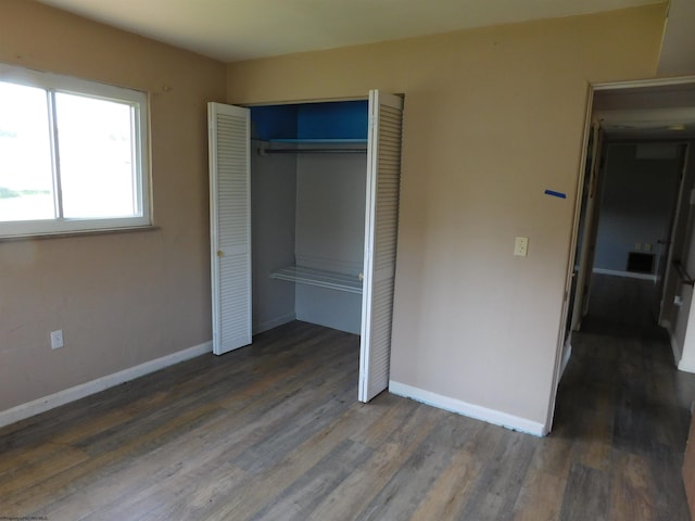 unfurnished bedroom with a closet and dark hardwood / wood-style floors