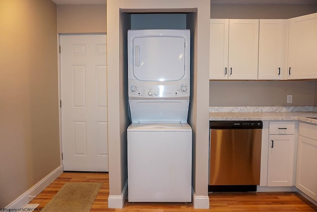 clothes washing area featuring light hardwood / wood-style flooring and stacked washer / dryer