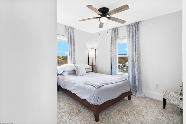 carpeted bedroom featuring multiple windows and ceiling fan