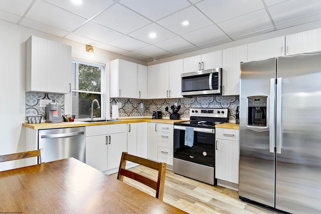 kitchen with sink, appliances with stainless steel finishes, white cabinets, and wood counters