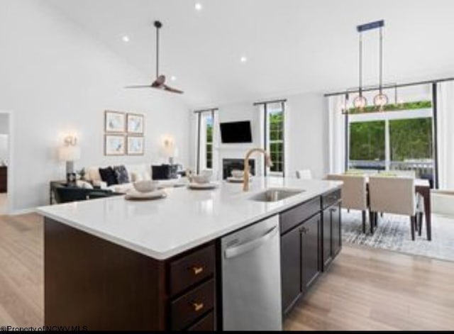 kitchen featuring pendant lighting, dishwasher, a center island with sink, and sink