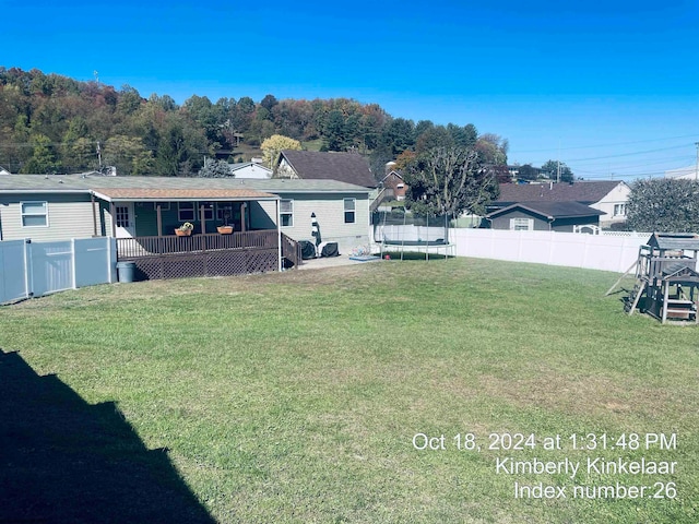 view of yard with a trampoline and a wooden deck