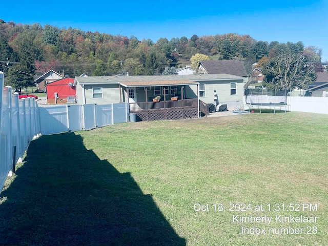 rear view of house featuring a trampoline and a lawn