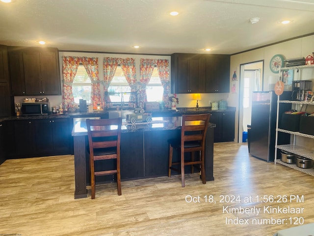 kitchen featuring a kitchen breakfast bar, dark brown cabinetry, and light hardwood / wood-style floors