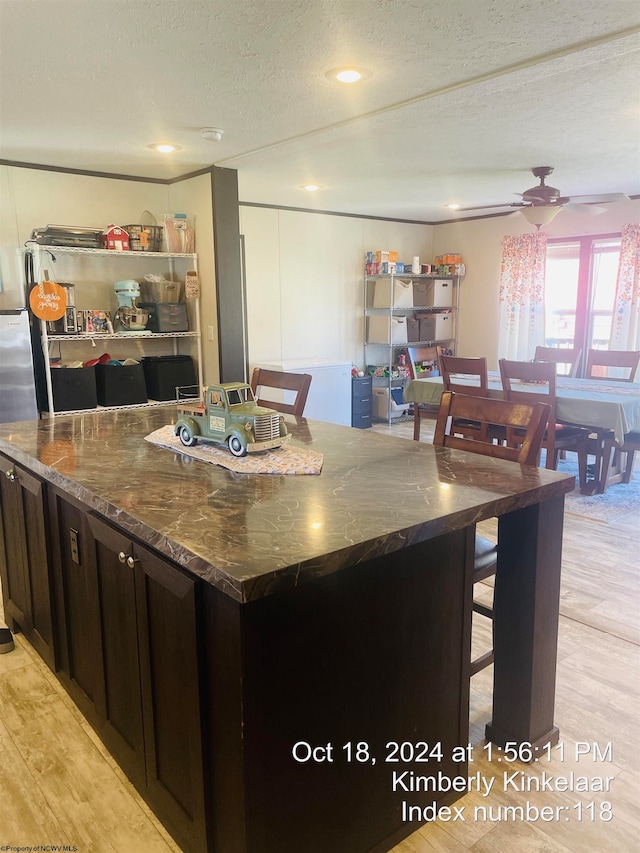 kitchen featuring a center island, ceiling fan, dark stone countertops, a textured ceiling, and light hardwood / wood-style floors