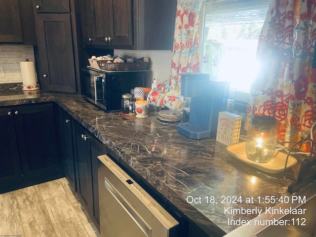 kitchen with dark brown cabinetry, dishwasher, tasteful backsplash, dark stone countertops, and light hardwood / wood-style floors