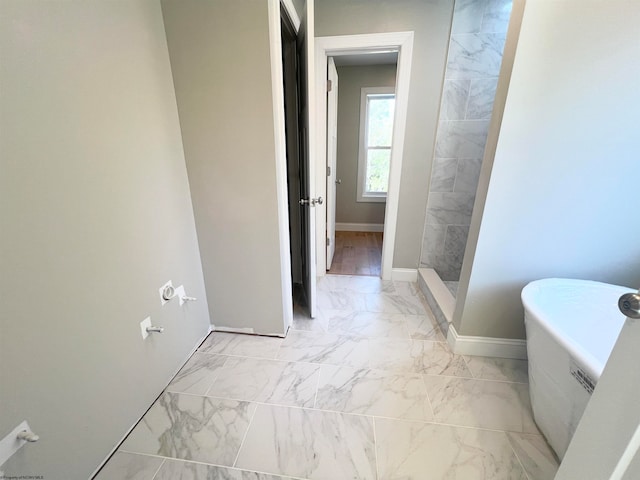 full bath with marble finish floor, tiled shower, a freestanding tub, and baseboards