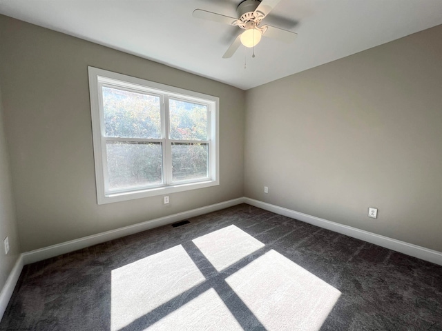 spare room featuring baseboards, visible vents, dark colored carpet, and a ceiling fan