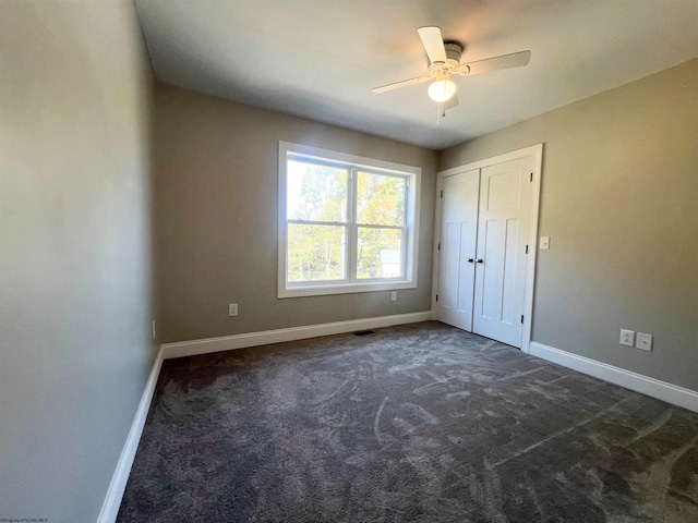 unfurnished bedroom featuring dark carpet, a closet, and ceiling fan