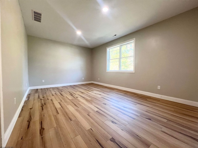 empty room featuring baseboards, visible vents, and light wood finished floors