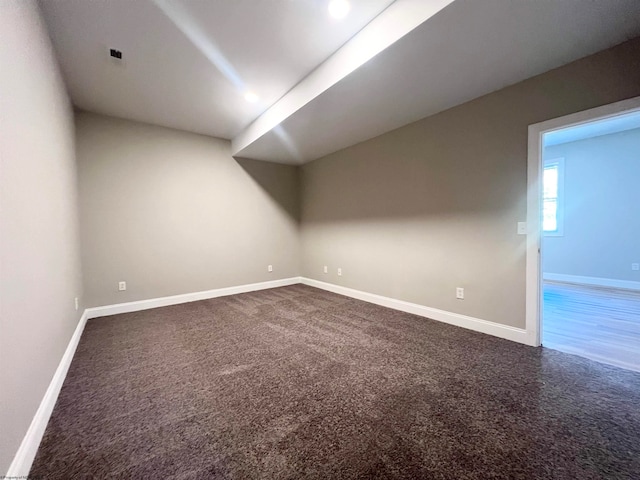 empty room with dark colored carpet and baseboards